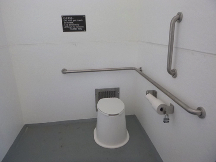 Accessible restroom – vault toilet – grab bars on the back and side – hard surface